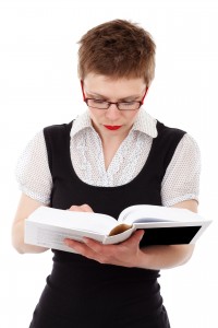 Female with glasses reading a textbook.