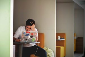 stressed out male student looking at his laptop