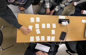 College students playing a memory game with index cards.