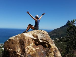 Woman on top of a mountain with hands raised in celebration