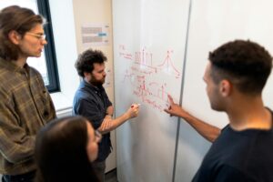 students working on an engineering problem on a whiteboard